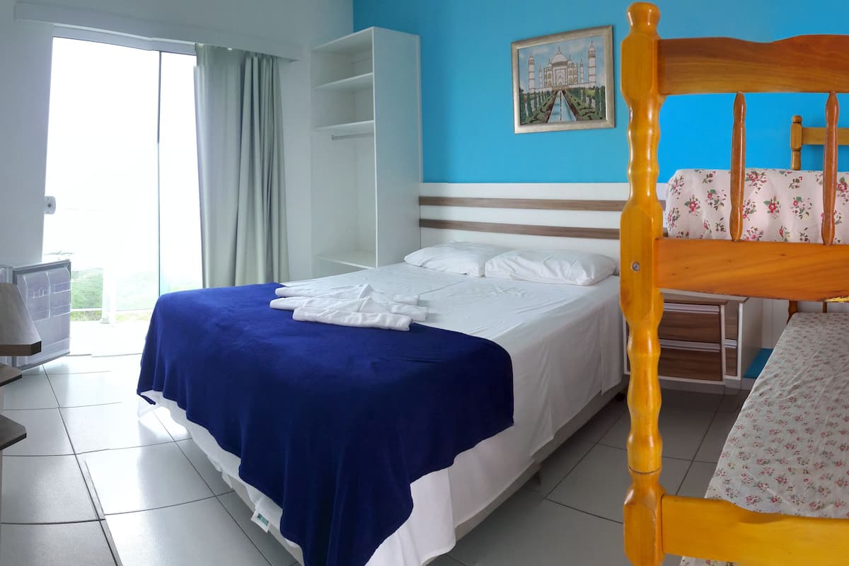 A hotel room with a bed, a desk, a chair, a TV, and a window with curtains.