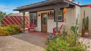 A small house with a covered porch, a red chair, and a cactus garden. - The Tucsonan Style Casita - FULLY FENCED AND PET FRIENDLY! (Tucson)