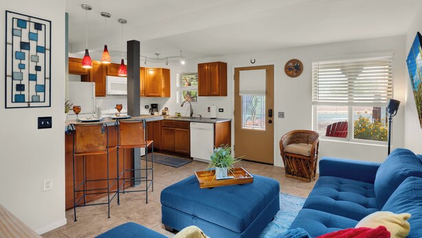 A modern kitchen with wooden cabinets, a bar stool, and pendant lighting. - The Tucsonan Style Casita - FULLY FENCED AND PET FRIENDLY! (Tucson)