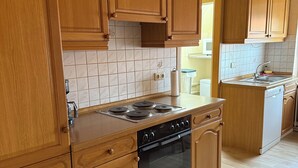 Cuina amb armaris de fusta, fornet i rentavaixelles.