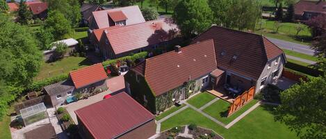 A residential area with multiple houses, each featuring red-tiled roofs and surrounded by green lawns and trees.
