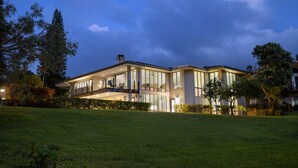 Une maison moderne à deux étages, dotée de grandes fenêtres, d’un balcon et d’une pelouse bien entretenue.