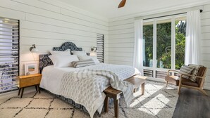 Une chambre à coucher avec un lit, des tables de chevet, une chaise et une fenêtre avec des rideaux.