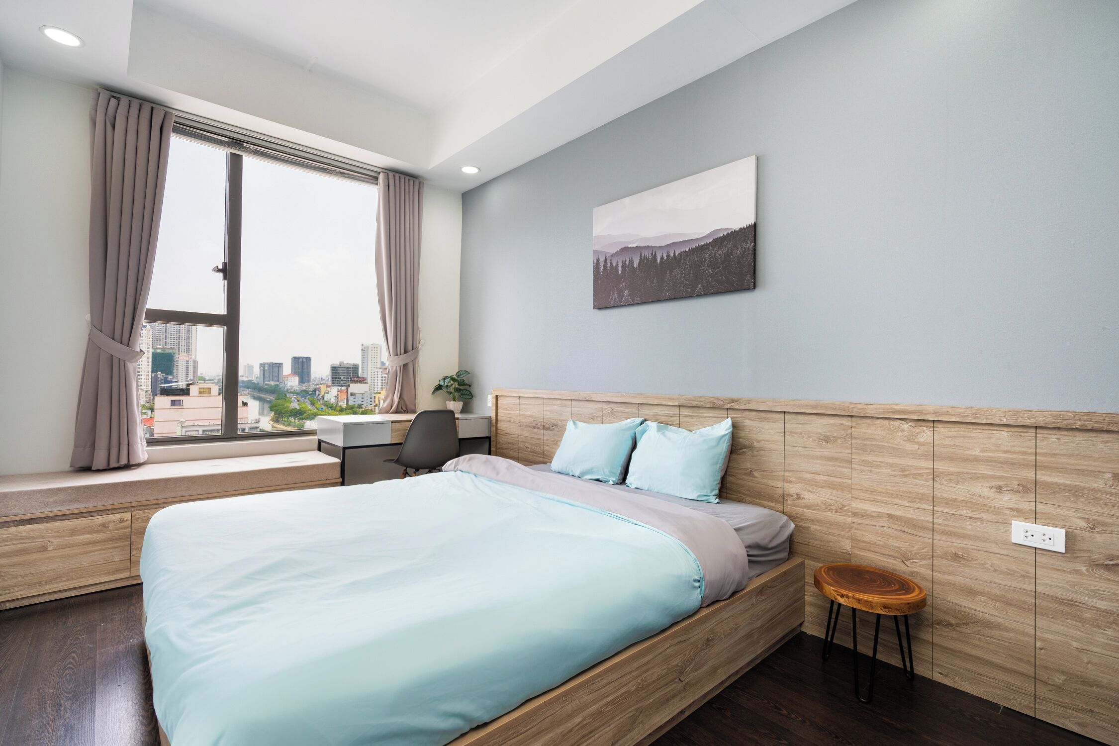 A modern bedroom with a large bed, a desk, and a window with curtains.