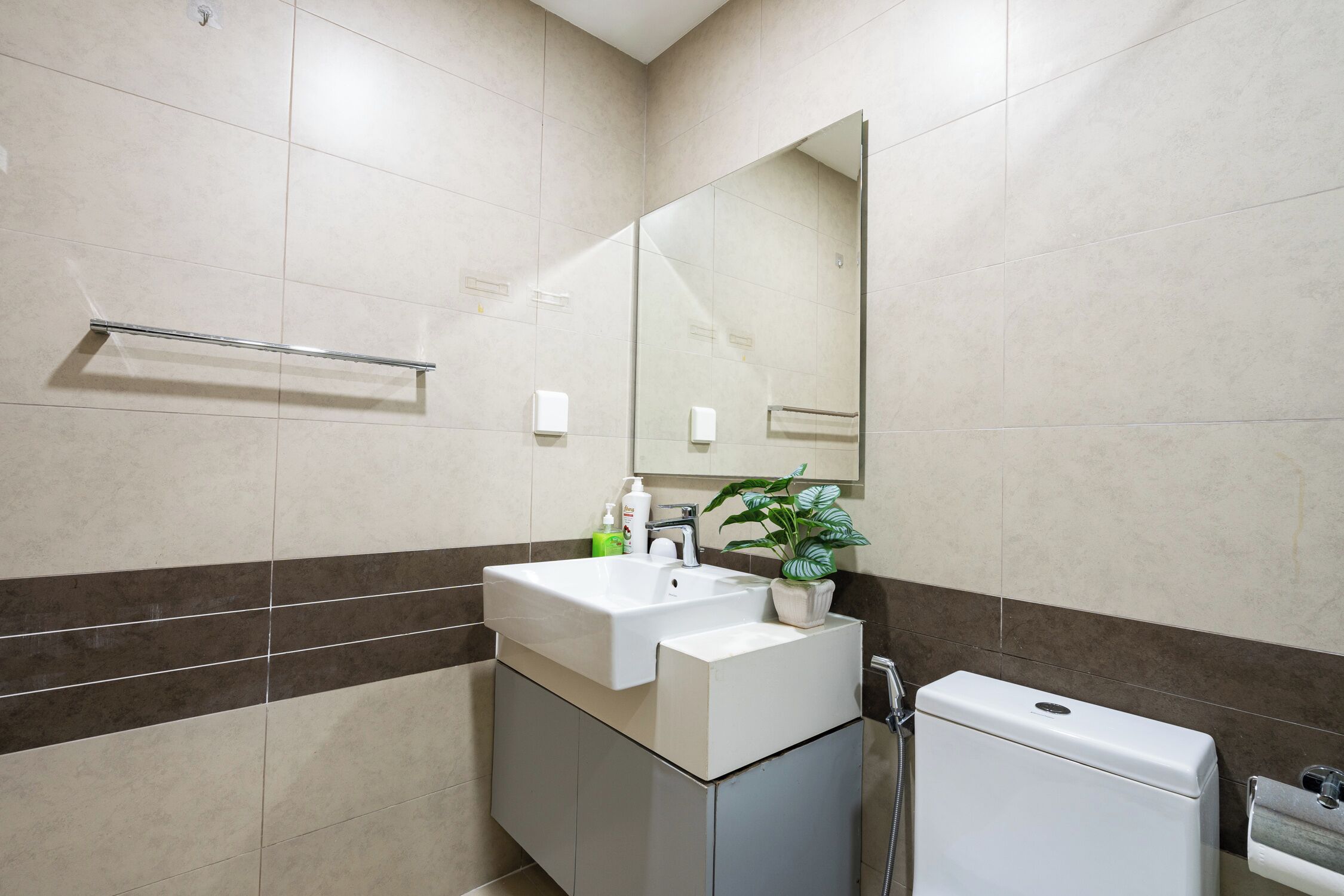 A modern bathroom with a white sink, mirror, and toilet.