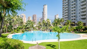 Un complexe hôtelier doté d’une grande piscine, de palmiers et, en arrière-plan, d’immeubles de grande hauteur.