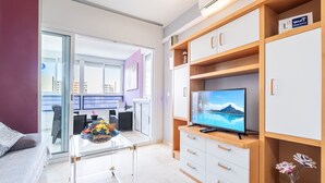 Un salon moderne avec une table basse en verre, un téléviseur à écran plat et un meuble en bois doté de tiroirs.