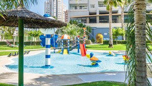 Un parc aquatique avec des toboggans et des aires de jeux, entouré de palmiers et, au fond, un bâtiment portant l’inscription « GIMNASIO CLUB SOCIAL ».