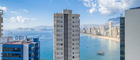 A high-rise hotel with a view of the sea and city skyline.