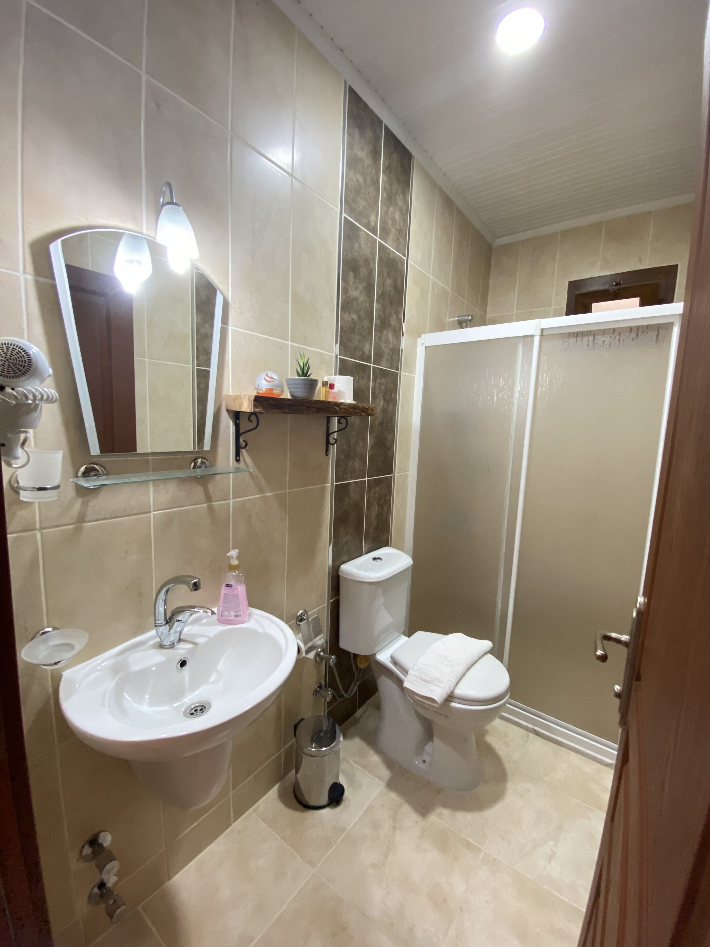 A bathroom with a sink, mirror, toilet, and shower.