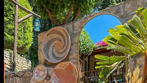 A stone wall with woven baskets, wooden benches, and a potted plant. - Faralya Misafir Evi (Fethiye)