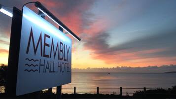 Placa do Hotel Membly Hall com vista para o pôr do sol sobre a água.