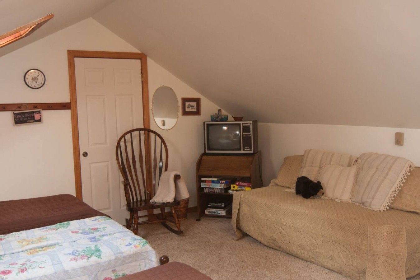 A small, cozy room with a bed, a chair, a television, and a couch.