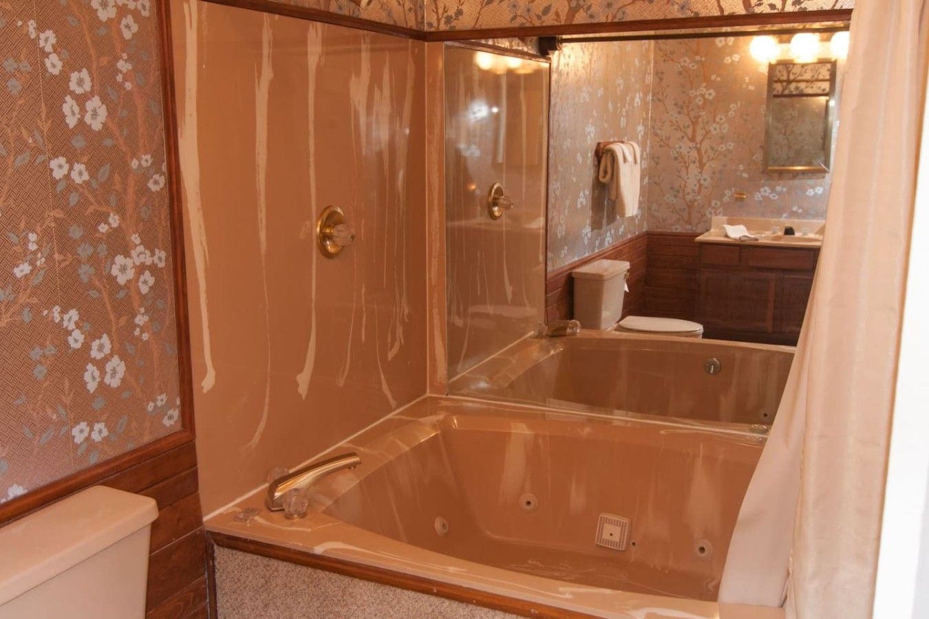 A bathroom with a glass-enclosed bathtub, a toilet, and a sink with a mirror above.