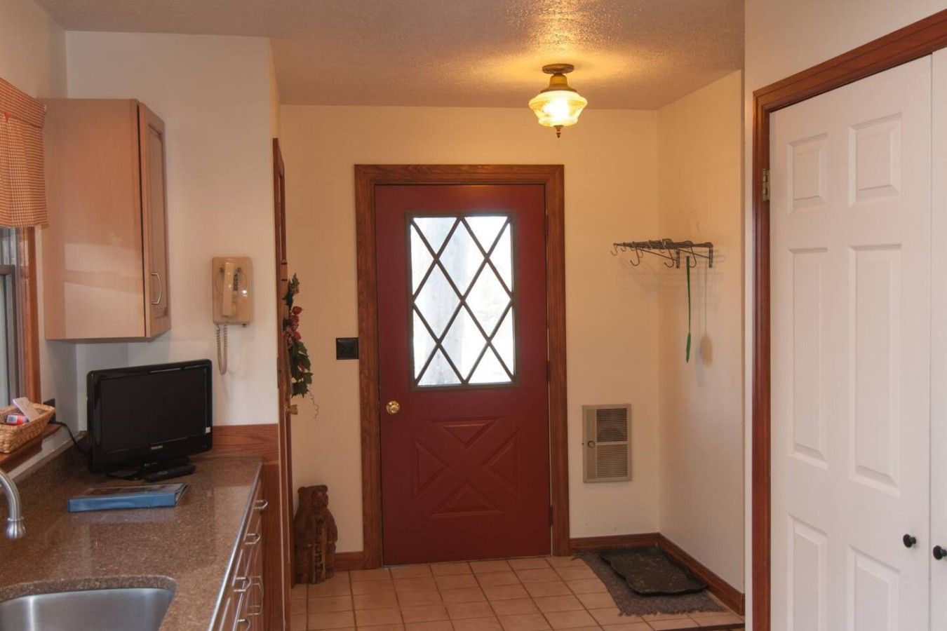 A kitchen with a built-in oven, a sink, and a countertop with a television.