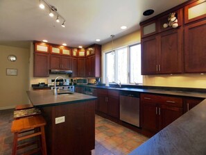A kitchen with wooden cabinets, a central island, a microwave, and a dishwasher.