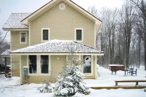Ein zweistöckiges Haus mit verschneietem Dach und einer Veranda.