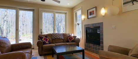 Una sala de estar con un sofá, sillones, una mesa de centro, chimenea y televisor.