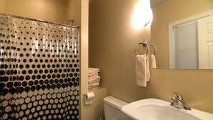 Ein Badezimmer mit Toilette, Waschbecken und einer Duschkabine mit Punkten.