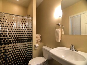 Un bagno con toilette, lavandino e tenda da doccia a pois.