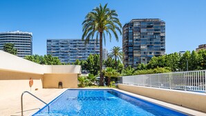 A rooftop swimming pool with a view of high-rise buildings and palm trees.