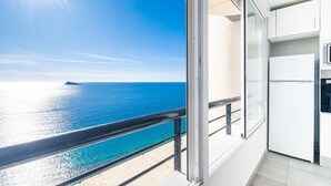A balcony with a view of the sea and a modern kitchen with a refrigerator.