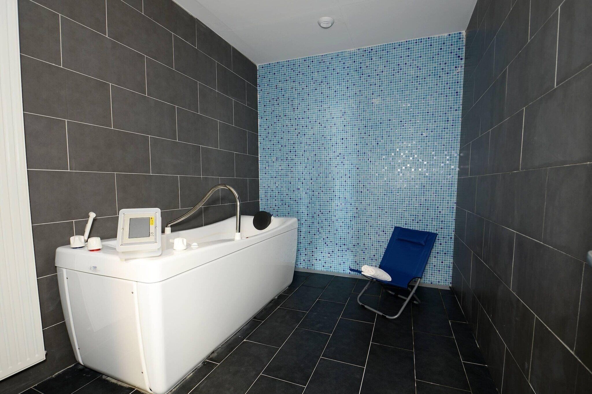 Baño con bañera, asiento de ducha y pared con azulejos.