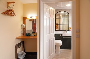 A bathroom with a white toilet, a sink, and a mirror. There is a towel rack and a hairdryer on the counter.