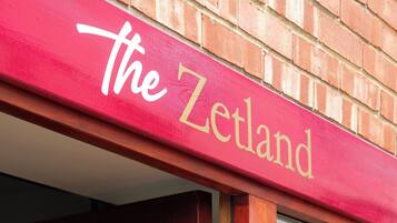 Un letrero rojo con la palabra 'Zetland' escrita en blanco.