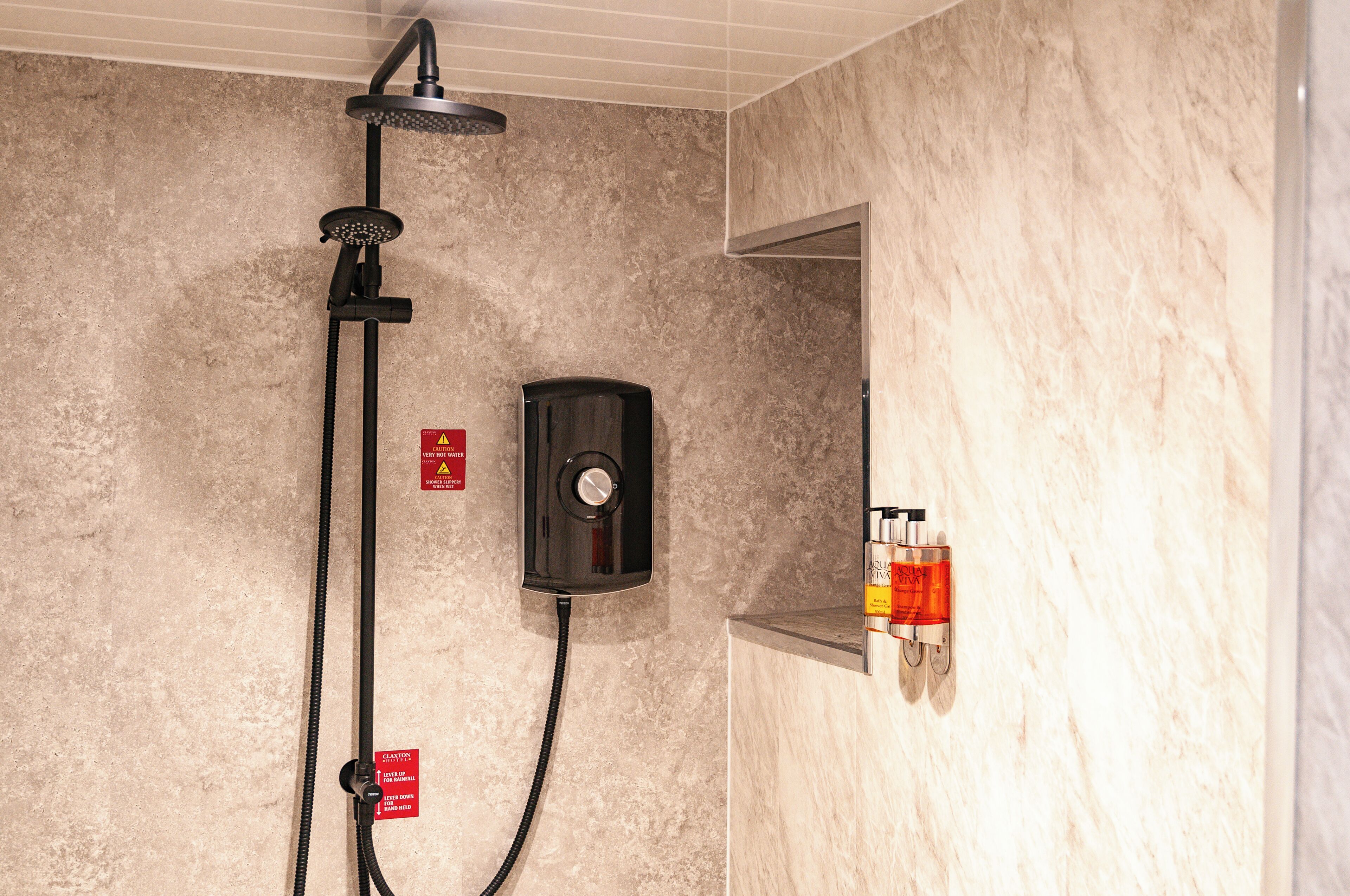Eine Dusche mit Handbrause, einer fest montierten Bedienfeld und einem Seifenspender.