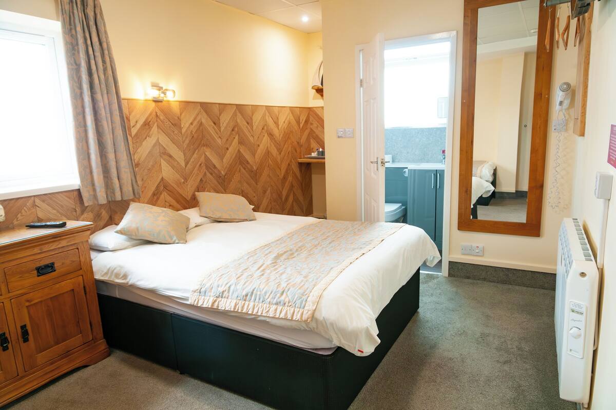 Une chambre à coucher avec un lit, une tête de lit en bois, une table de chevet et un miroir.