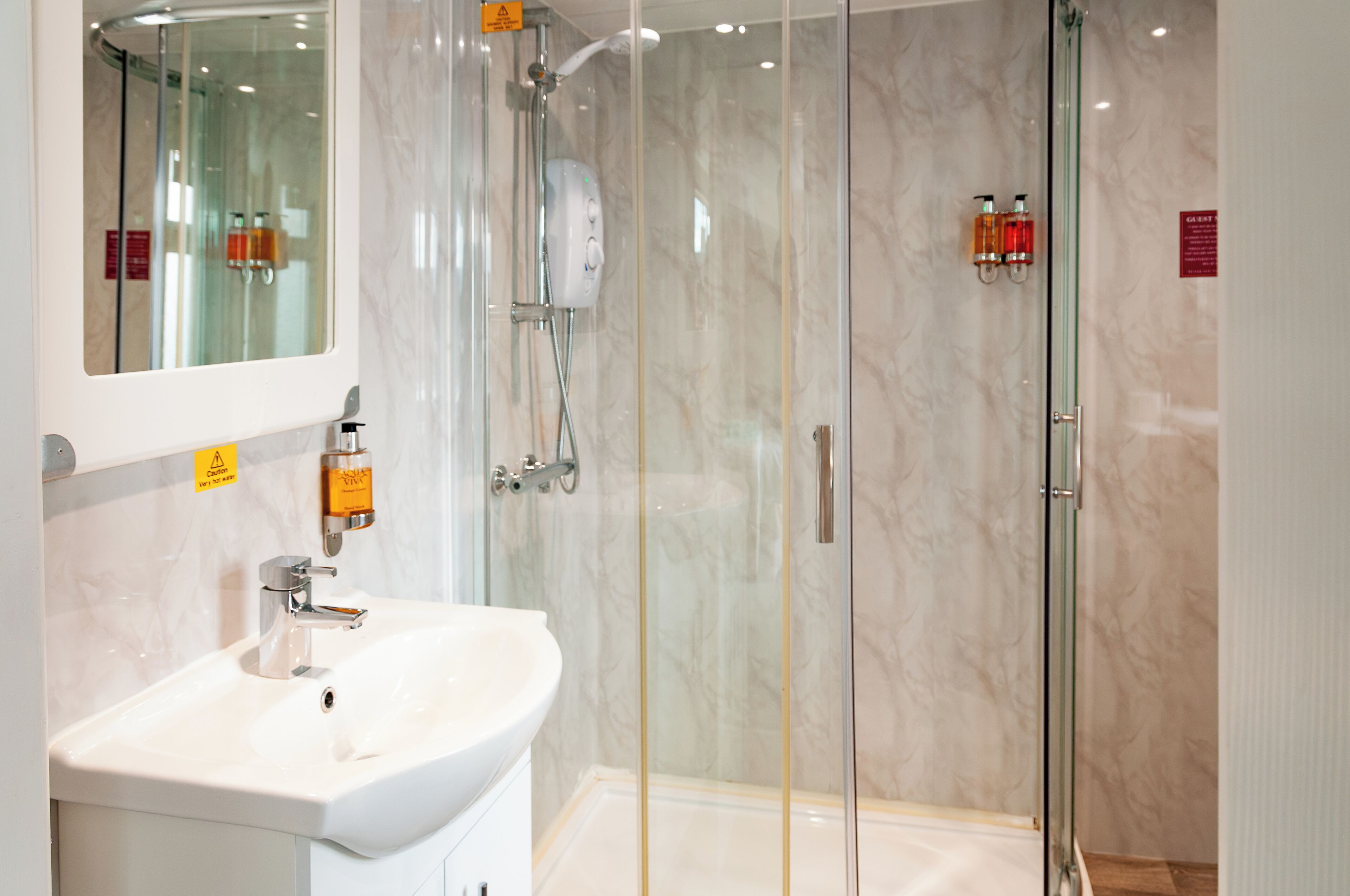 A modern bathroom with a glass-enclosed shower, a white sink, and a mirror.