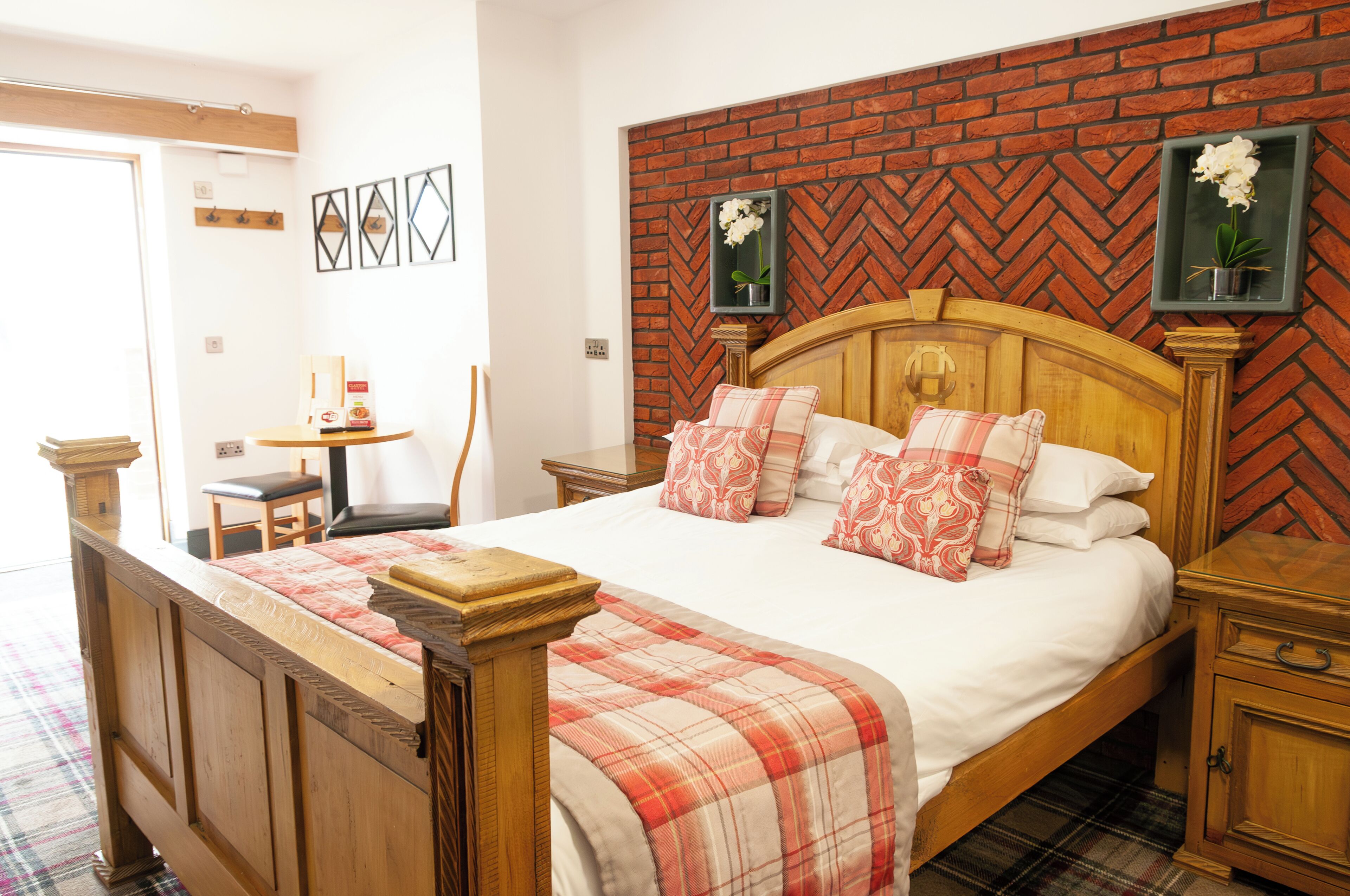 A bedroom with a wooden bed, a brick-patterned headboard, two bedside tables, and a plaid bedspread.