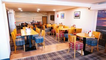 A dining area with multiple tables and chairs, some with plaid upholstery.