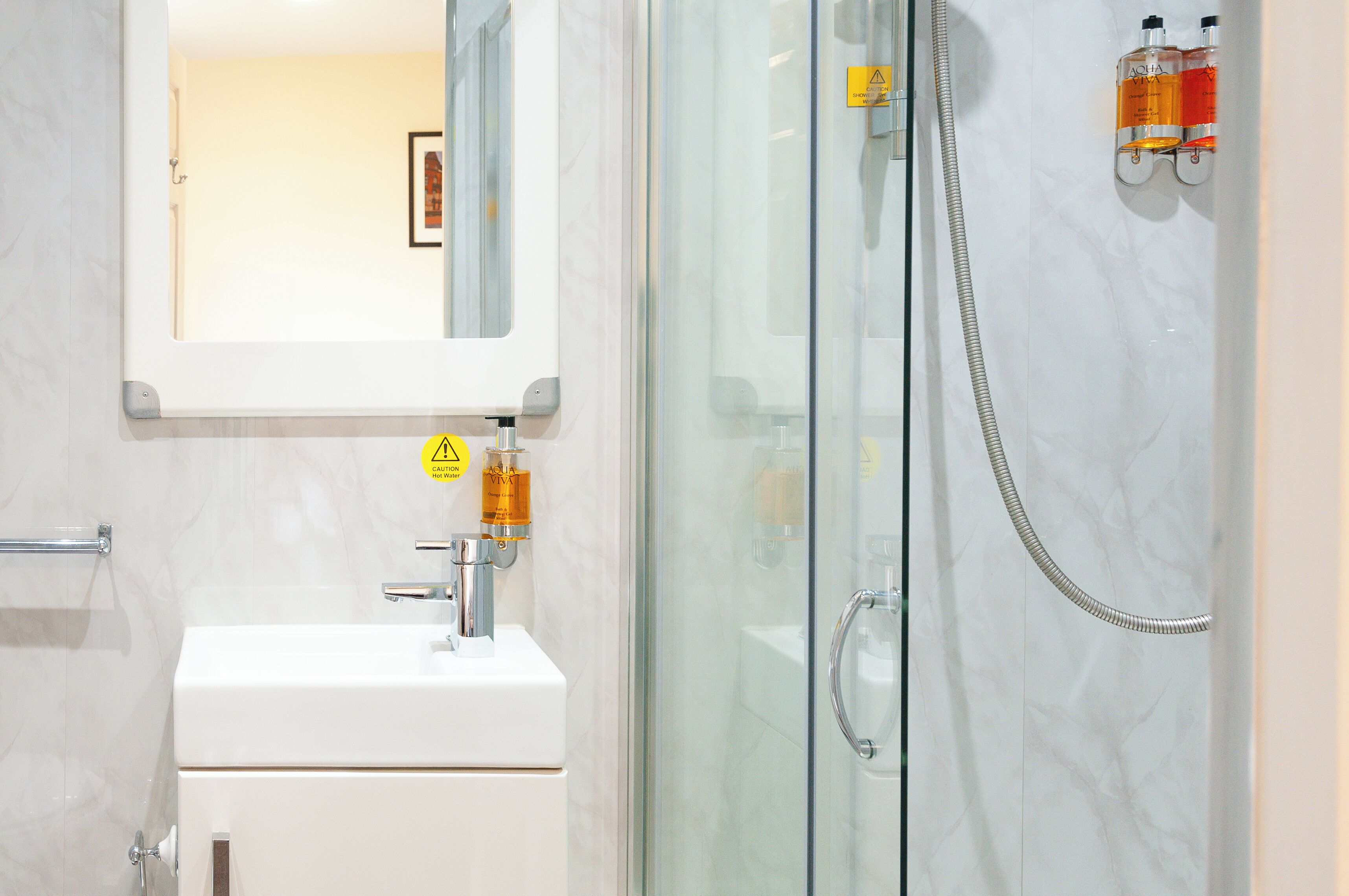Une salle de bain avec une douche à parois de verre, un lavabo blanc et un miroir au-dessus du lavabo.