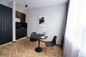 A modern kitchen with black cabinets, a black dining table, and two black chairs. There is a framed picture on the wall and a vase with flowers on the table. - V Business Apartments Stuttgart Magstadt (Magstadt)