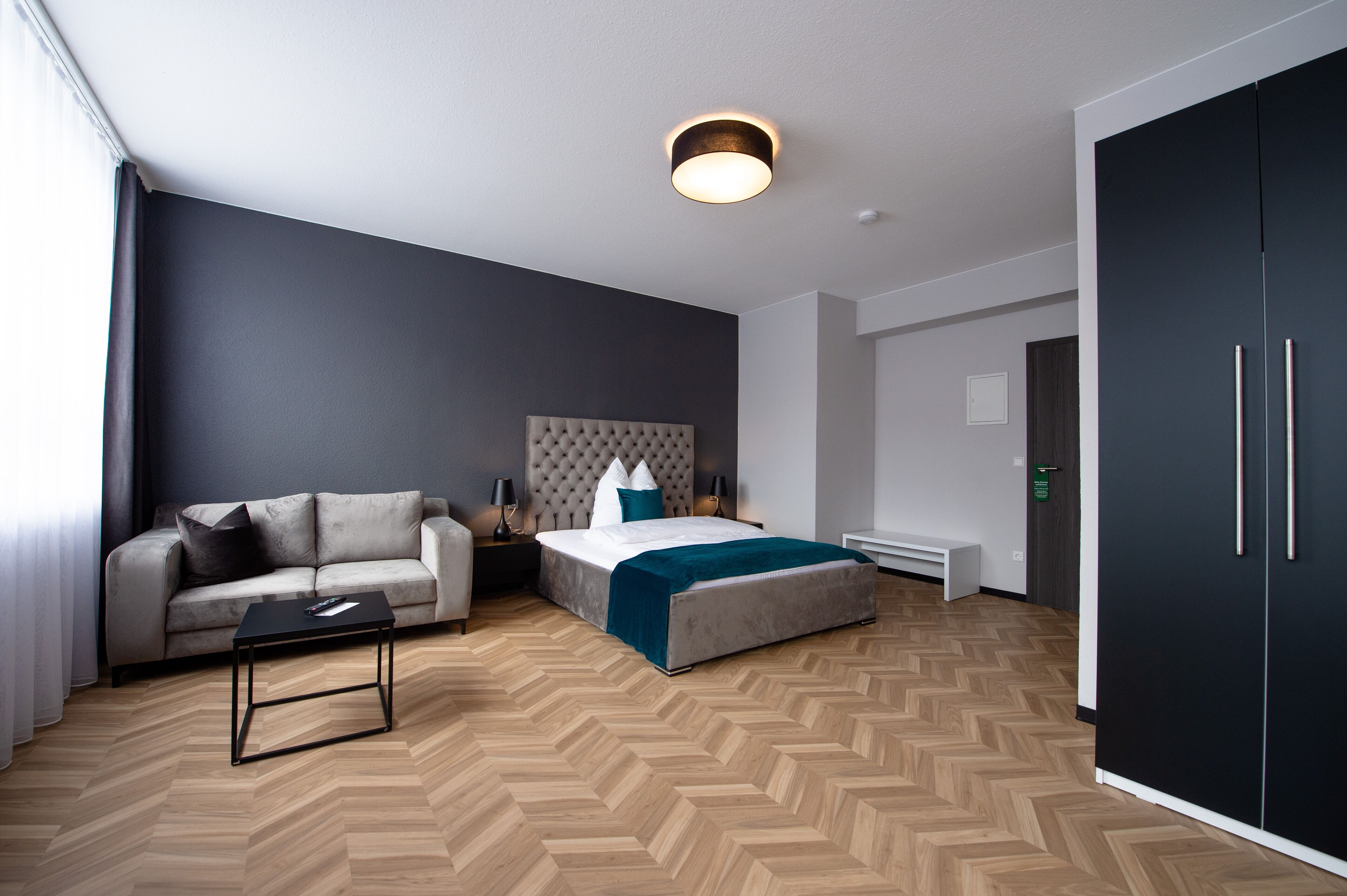 Une chambre d’hôtel moderne équipée d’un lit, d’un canapé, d’une table basse et d’une armoire.