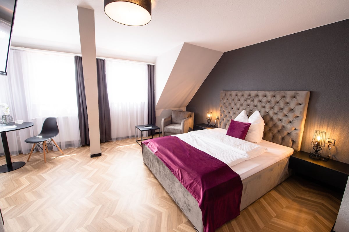 A modern hotel room with a large bed, a desk, and a chair.