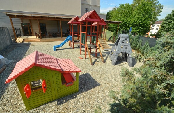 A playground with a slide, climbing structures, and a small playhouse. - Hotel Chmelnice (Napajedla)