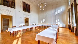 A large conference room with a long table set for meetings, high ceilings, and classical architectural details. - Hotel Chmelnice (Napajedla)