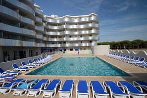 A swimming pool with sun loungers and a multi-story building with balconies. - Apartment in Le Barcarès with Sea View (Le Barcares)