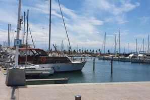 A marina with multiple boats docked, a clear sky, and a calm water surface. - Seaside Escape with Pool (Le Barcares)
