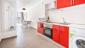 Una cocina moderna con armarios rojos, un microondas, una estufa y un lavavajillas.