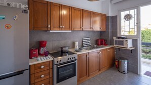 A modern kitchen with wooden cabinets, a stainless steel refrigerator, a gas stove, and a microwave. - Voula- Archer Amazing Sea View Apartment (Vari-Voula-Vouliagmeni)