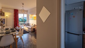 A modern kitchen with a stainless steel refrigerator, a dining area with a table set for four, and a living area with a sofa and a coffee table. - Voula- Archer Amazing Sea View Apartment (Vari-Voula-Vouliagmeni)