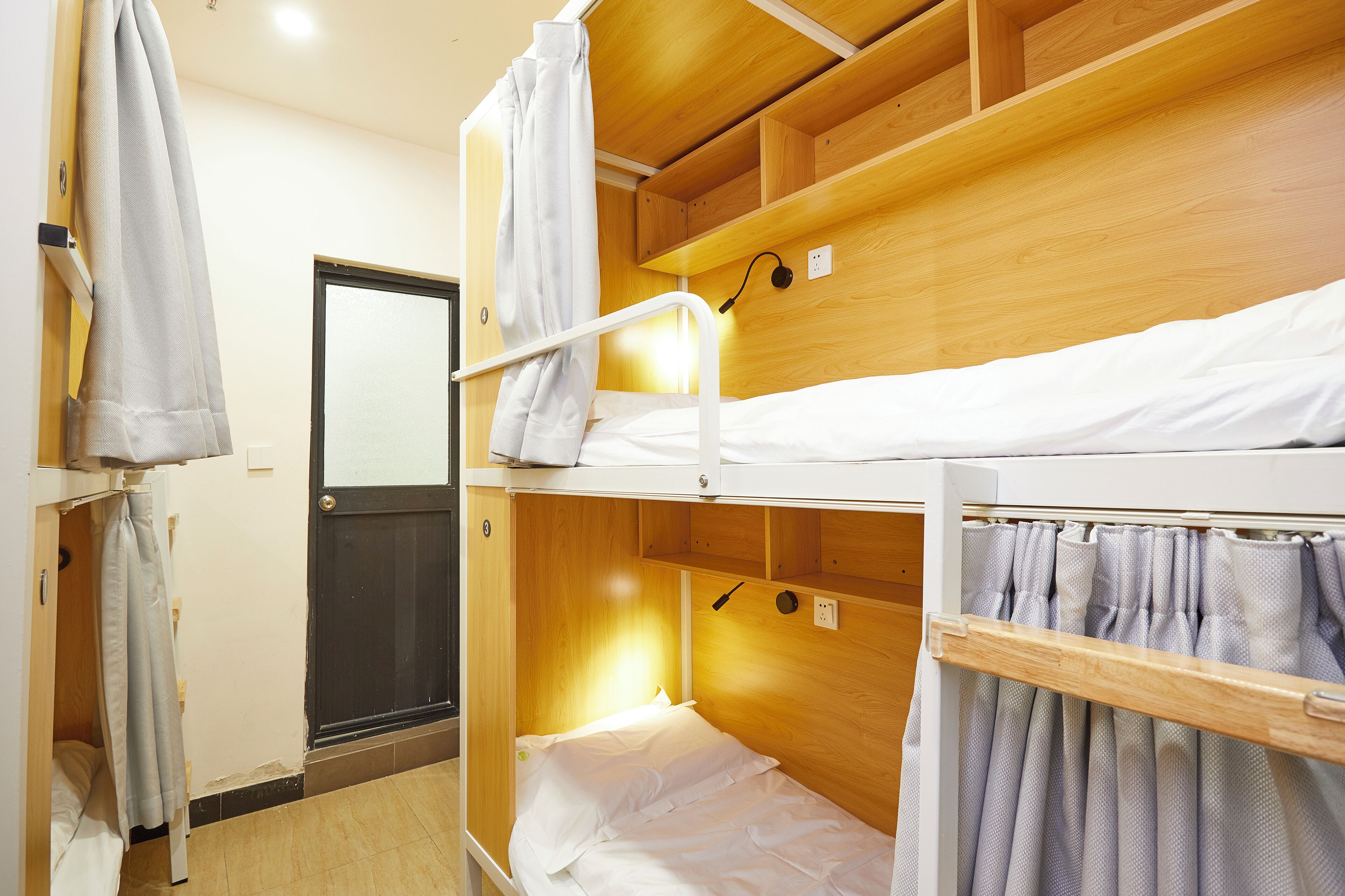 A bunk bed room with wooden walls, a door, and a curtain.