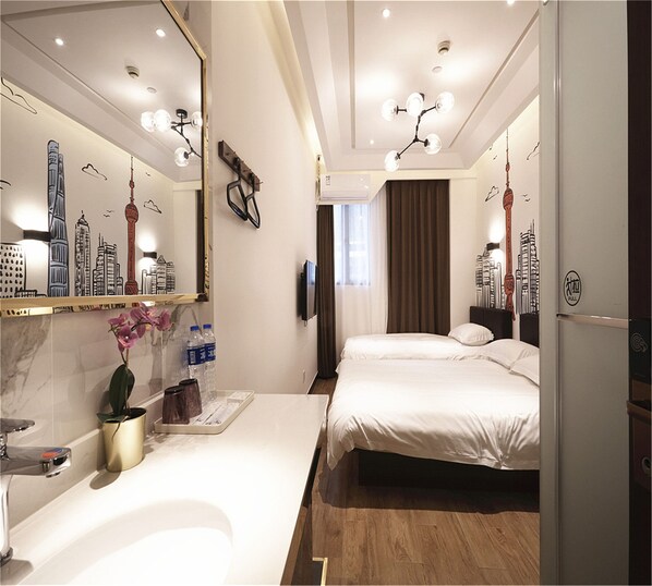 Una habitación de hotel con un espejo grande, una cama, una mesita de noche y un baño con lavamanos y ducha.