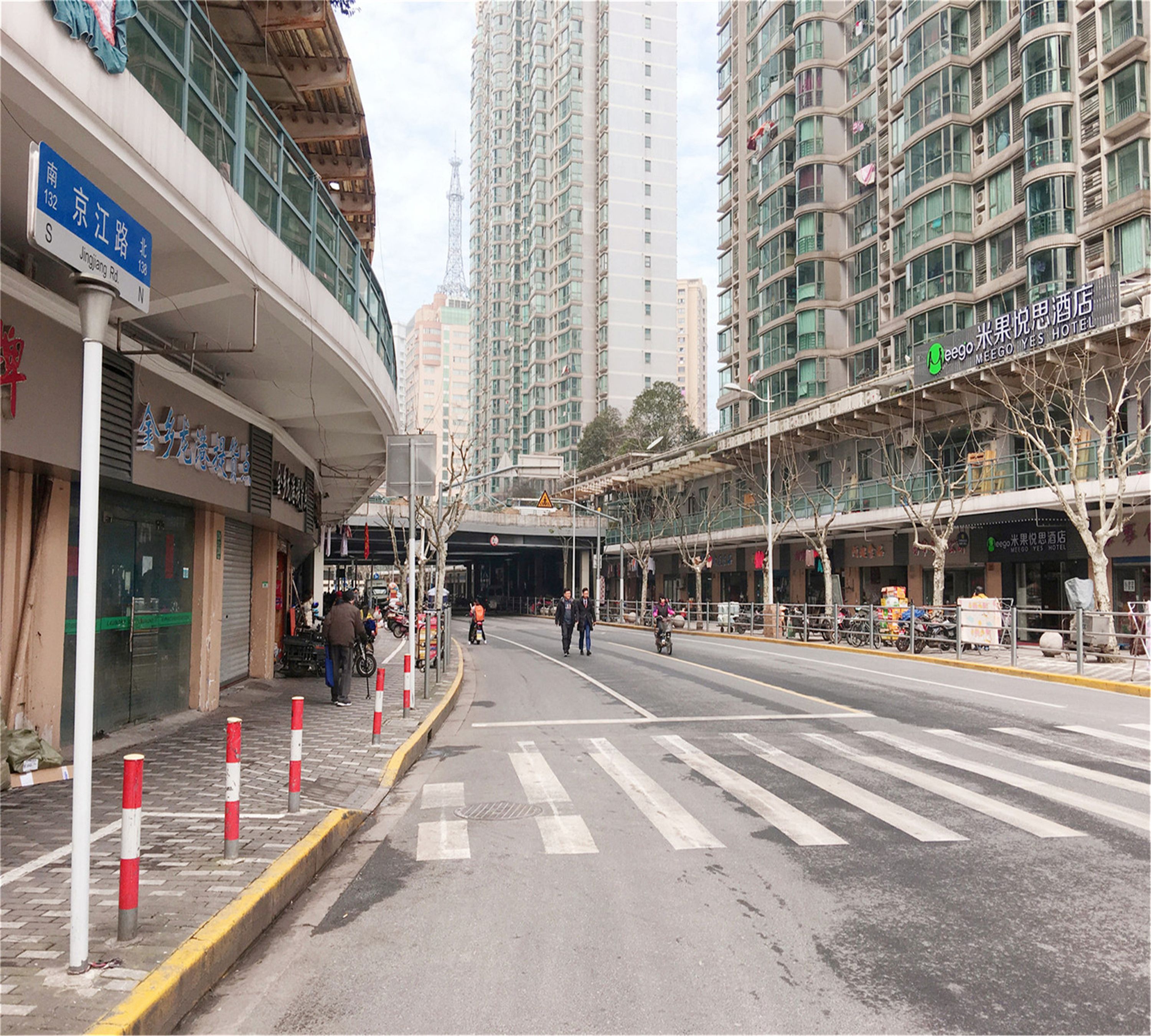 A street view with a hotel named "MeeGo Yes Hotel" on the right, a pedestrian crossing, and high-rise buildings in the background.