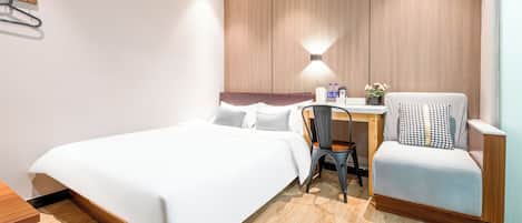 Una camera d'albergo con un letto, una scrivania, una sedia e una lampada a parete.