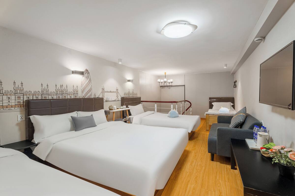 A hotel room with two beds, a sofa, a desk, and a wall mural.